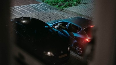 Geregisseerde foto van een drugsdeal, twee auto's in het donker, gezien vanuit woning, campagnebeeld Houd misdaad uit je buurt